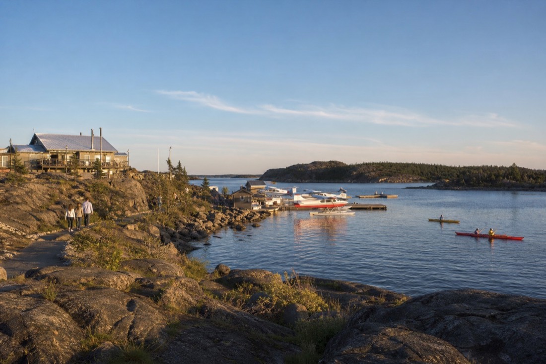 Summer afternoon in Yellowknife Old Town with kayaks on the bay, floatplanes at the dock and people walking the shoreline